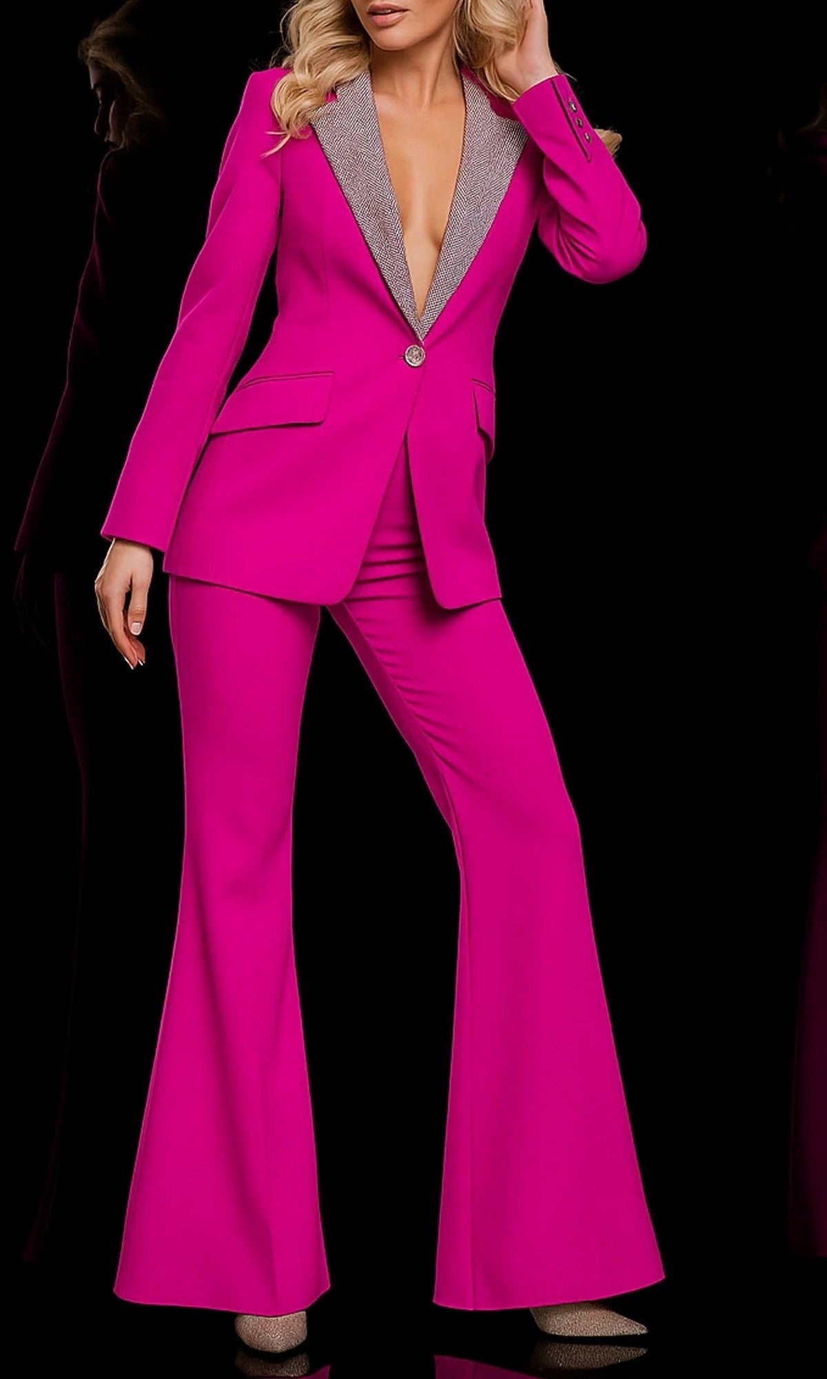 A person wearing the Jovani 23336 long jumpsuit in fuchsia, featuring a silver lapel, poses against a black background.